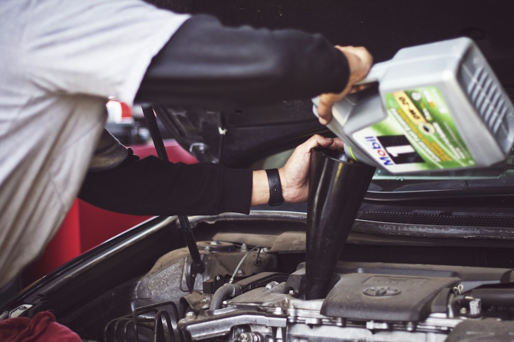 Technician adding engine oil during a vehicle service